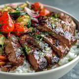 Tender sirloin and charred bell peppers rest on fluffy rice in the savory Sheet Pan Steak and Veggie Bowl.