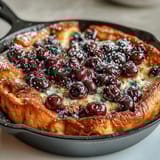 Fluffy baked pancake casserole loaded with juicy blueberries, golden and tender, ready for a cozy brunch table.  