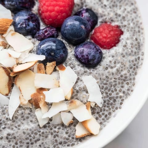 Creamy poppy seed chia pudding layered in a glass jar, topped with fresh blueberries and toasted almonds for a healthy breakfast.