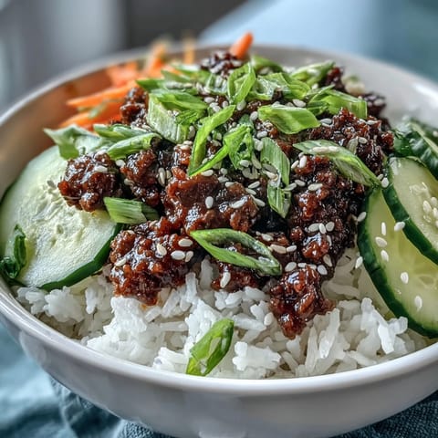 Close-up photo of a Korean Ground Beef Bowl garnished with sesame seeds and fresh green onions on a rustic table.