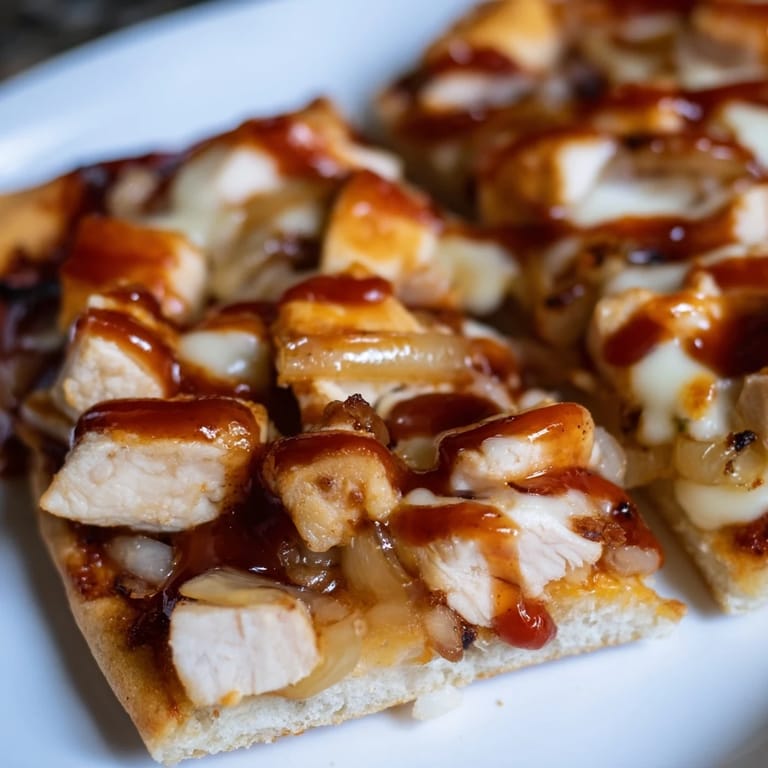 A rustic kitchen setting with a hot BBQ Chicken Flatbread on a baking sheet, highlighting bubbly cheese and savory toppings.