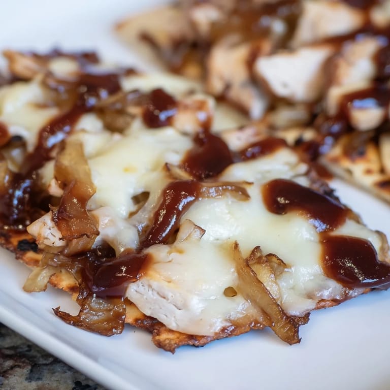 Sliced wedges of BBQ Chicken Flatbread on a wooden board, drizzled with tangy sauce and fresh cilantro, ready for serving.