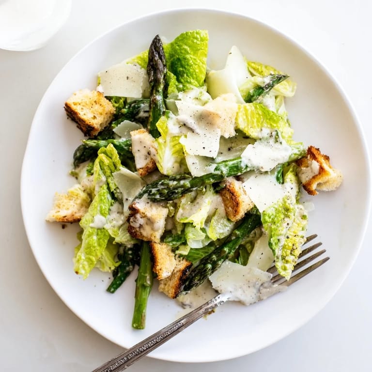 Homemade croutons and shaved Parmesan cheese top a vibrant Roasted Asparagus Caesar Salad, perfect for a fresh spring dinner.