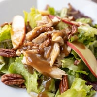 A vibrant Caramel Apple Chicken Salad with tender chicken, crisp apples, and candied pecans on mixed greens.